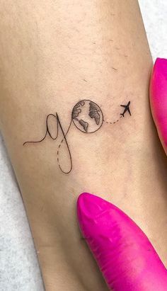 a woman's foot with an airplane flying over the earth tattoo on her left ankle