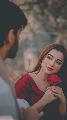 a woman holding a red rose in her hand