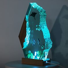 an illuminated sculpture with people swimming in the water and underwater creatures on it's sides