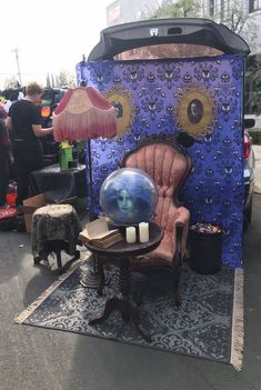 a chair with a glass ball on it sitting in front of a blue tent that has a woman's face inside