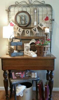 a wooden table topped with lots of clutter next to a wall mounted sign that says love