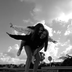 two young women are riding on the back of a skateboard in black and white