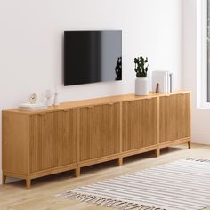 a television mounted on the wall above a wooden cabinet in a room with white walls