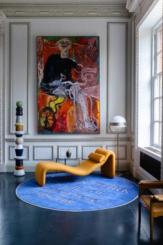 a living room with a large painting on the wall and blue rugs in front of it