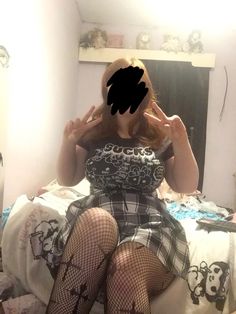 a woman sitting on top of a bed wearing fishnet stockings and holding her hands up to her face