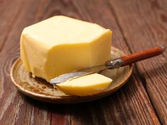 a piece of butter is on a plate with a knife and some sort of cheese