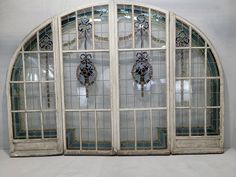 an arched window with stained glass panels and decorative decorations on the windowsill, in front of a white wall