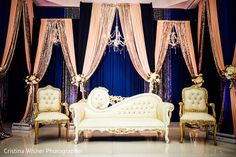 an elaborately decorated stage with couches and chandeliers for a wedding ceremony