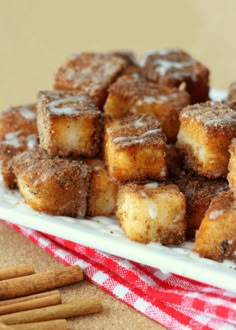 a white plate topped with small pieces of cake next to crackers and cinnamon sticks