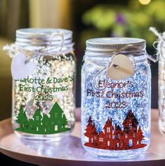 three mason jars decorated with personalized christmas labels and glittery snowflakes are sitting on a table