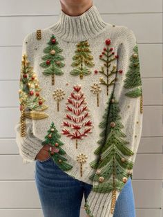 a woman wearing a white sweater with christmas trees on it and gold ornaments around the neck