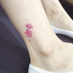 a pink flower tattoo on the ankle