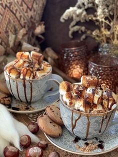 two cups filled with hot chocolate and marshmallows on top of saucers