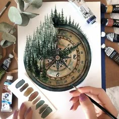 someone is painting a compass with trees on it