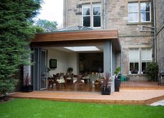 an open patio with wooden decking in front of a large brick building and green grass