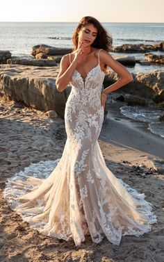 a woman standing on top of a beach next to the ocean wearing a wedding dress