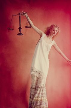 a woman standing in front of a scale with her arm raised and the scales above her head