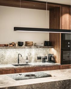 a modern kitchen with marble counter tops and wooden cabinetry is pictured in this image