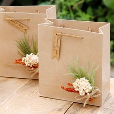 two brown paper bags with flowers on them sitting on top of a wooden table next to each other