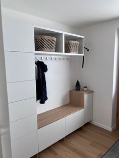 a white closet with shelves and baskets on the wall, next to a wooden floor