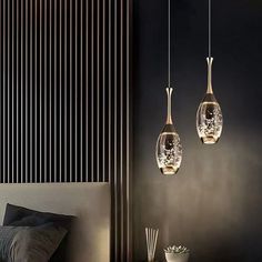 three hanging lights in the shape of vases on a wall next to a bed