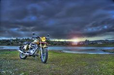 a motorcycle parked on top of a grass covered field next to a body of water