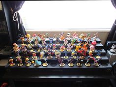 a bunch of toy figurines sitting on top of a shelf in front of a window