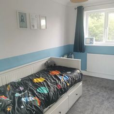 a bedroom with a bed, dresser and window in the corner that has blue walls