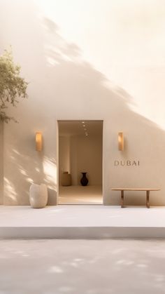 a white building with a bench in front of it and a tree on the other side