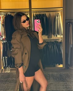 a woman taking a selfie in front of a closet with clothes and handbags