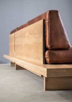 a brown leather couch sitting on top of a wooden table next to a gray wall