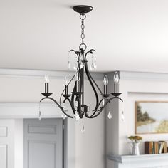 a black chandelier hanging from the ceiling in a room with white walls and fireplace