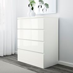 a white dresser with three vases on top