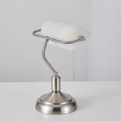 a silver desk lamp on a white table