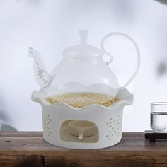 a glass tea pot filled with yellow liquid on top of a wooden table next to a water dispenser