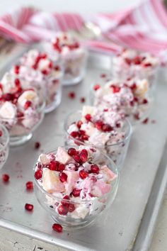 small bowls filled with food sitting on top of a metal tray covered in pomegranates