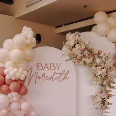 balloons and flowers decorate the backdrop for a baby shower