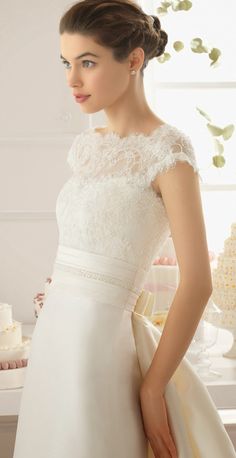 a woman in a white dress standing next to a cake