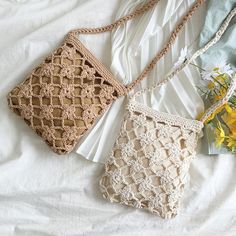 two crocheted purses sitting on top of a bed next to yellow flowers