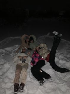 three people laying in the snow at night