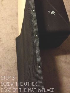 a black bag sitting on top of a carpeted floor next to a white wall