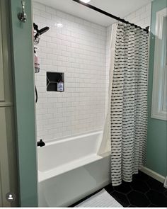 a white bath tub sitting next to a shower in a bathroom under a light fixture