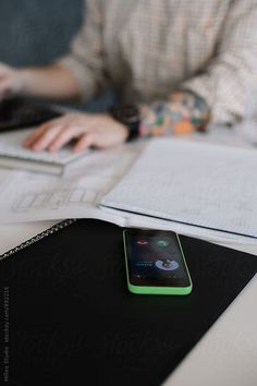 a cell phone sitting on top of a desk next to a laptop computer and notebook