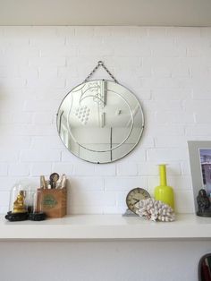 a white brick wall with a round mirror on it's mantle and various decorations