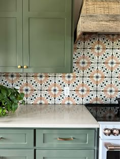 a kitchen with green cabinets and tile backsplash, white stove top and oven