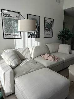 a living room with white furniture and pictures on the wall above it's couch