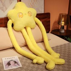 an octopus stuffed animal sitting on top of a bed next to a magazine and lamp