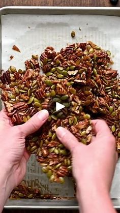 two hands are grabbing seeds from a tray