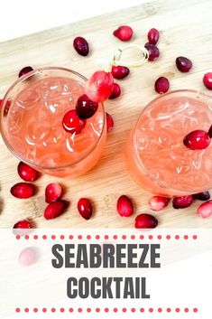 two glasses filled with ice and pomegranate on top of a cutting board