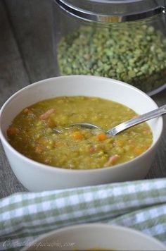 there is a bowl of soup on the table with a spoon in it and another bowl next to it